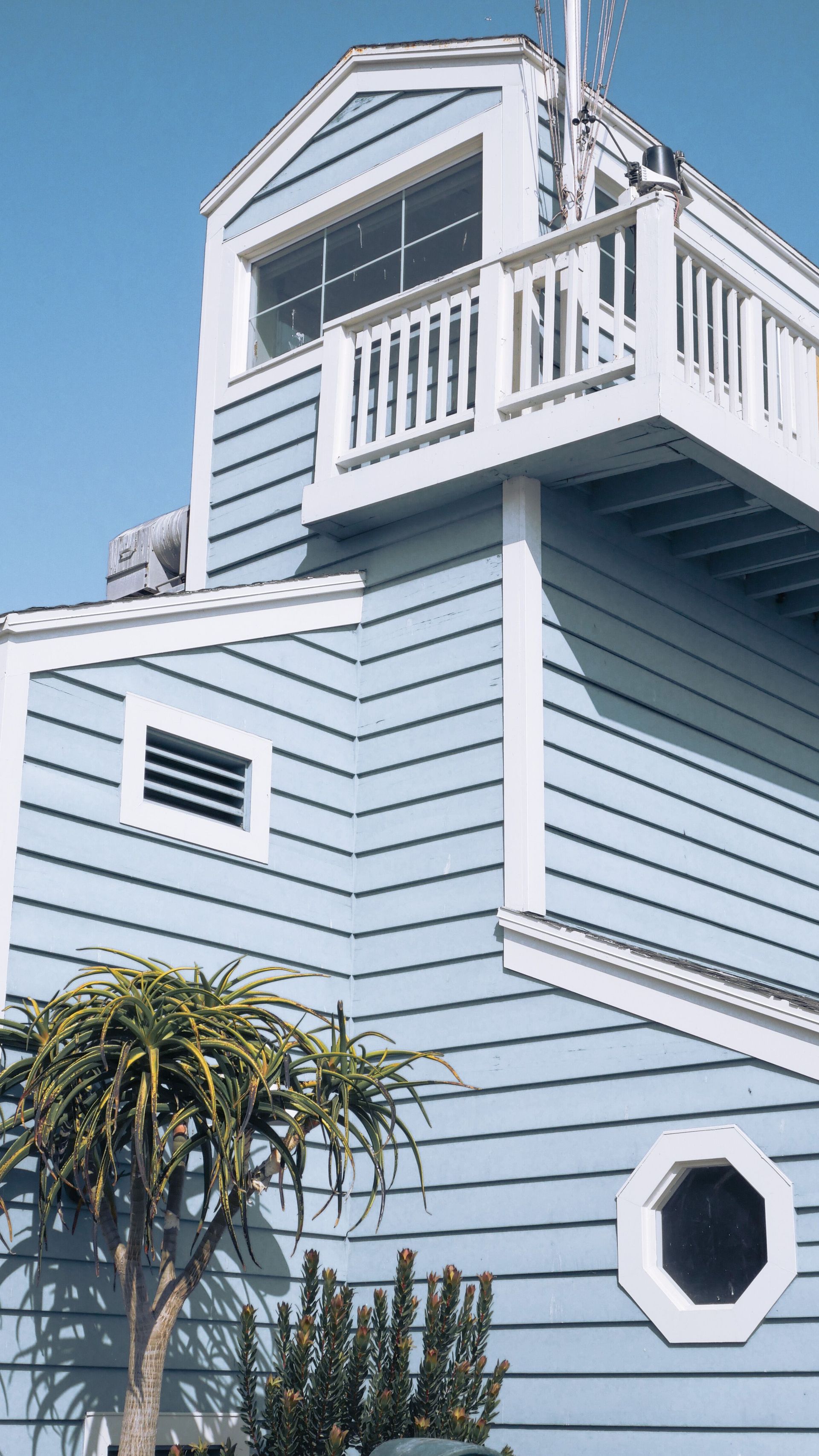 Vertical view of a charming blue beach house facade on a sunny day in Newport Beach.