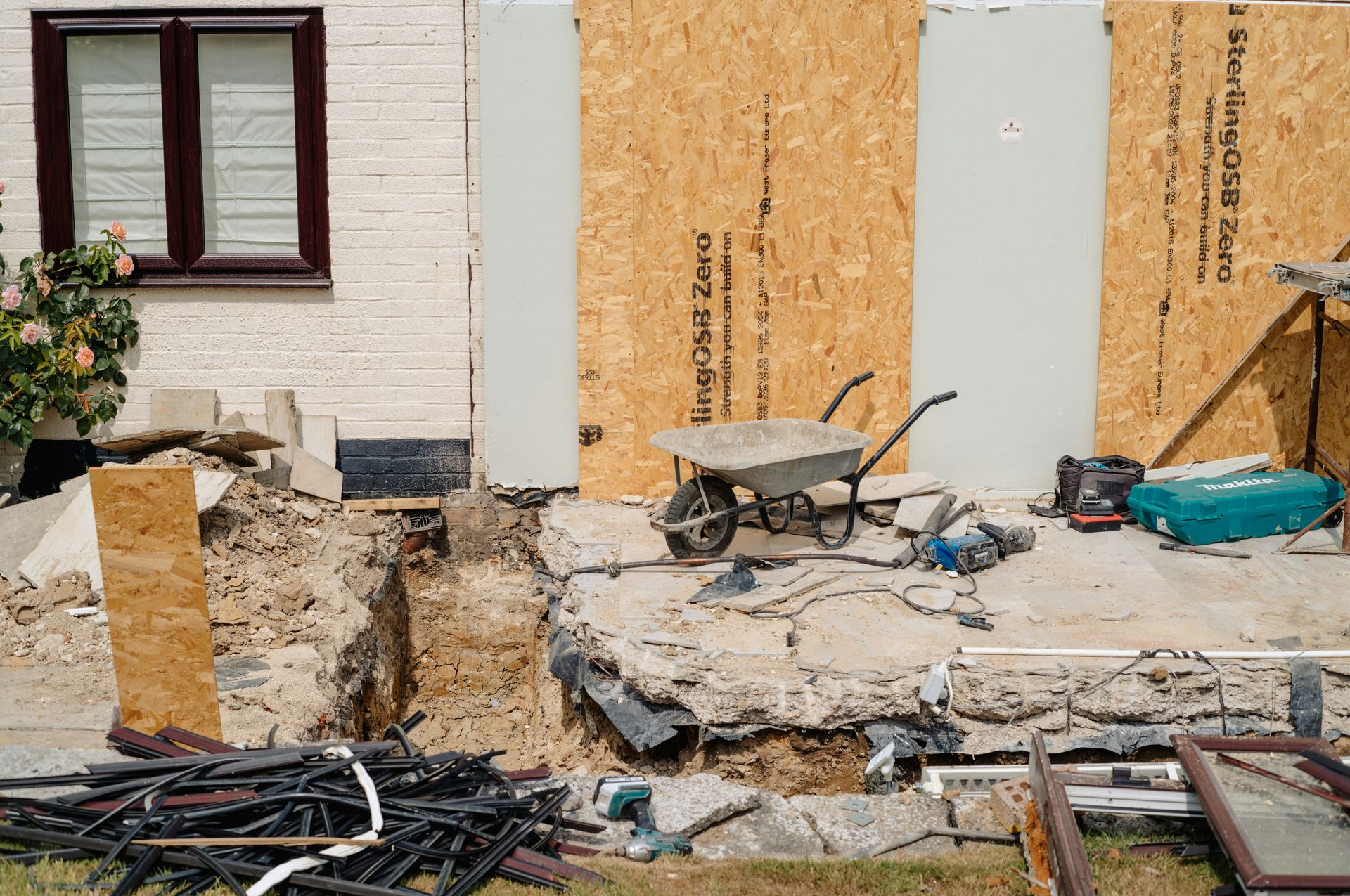 House renovation with exposed foundation and construction equipment